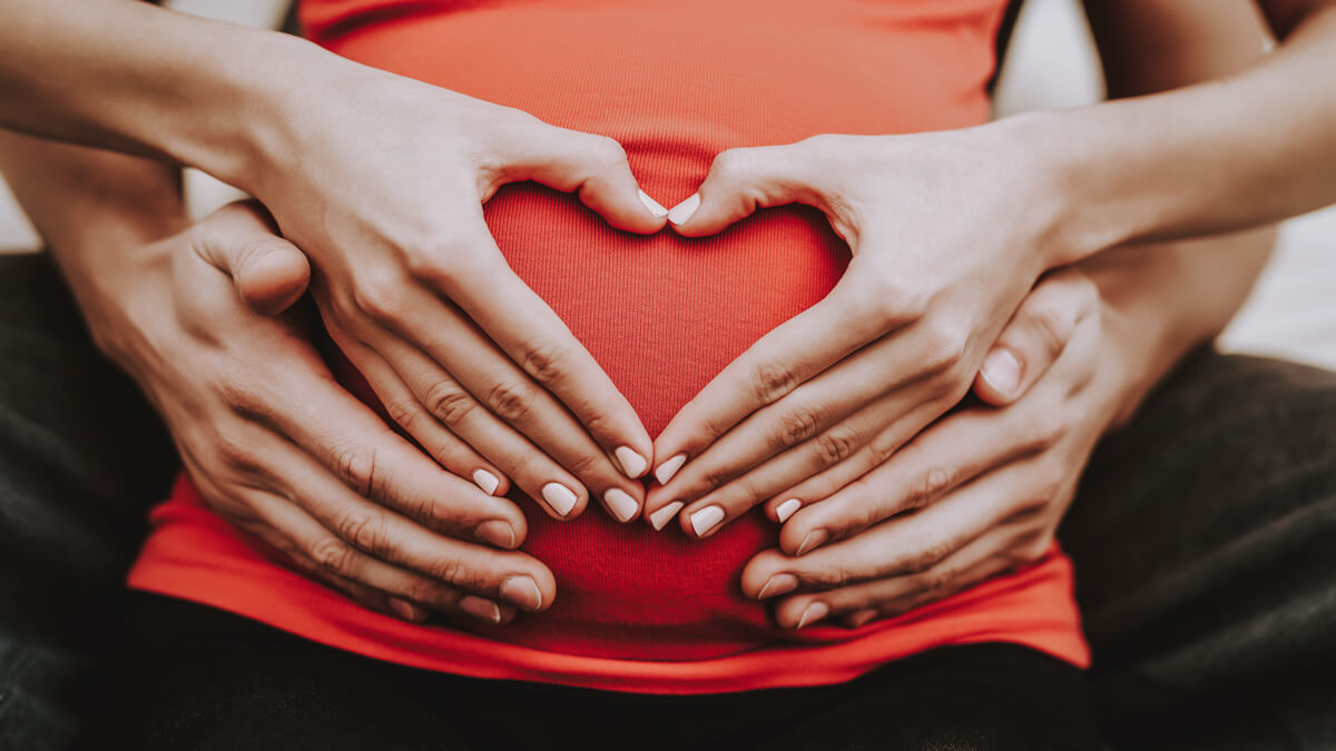 Couples makes heart on pregnant belly